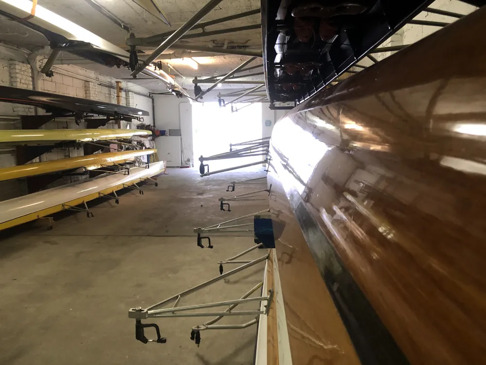 Blick in die Bootshalle mit Rennbooten auf Regalen entlang der Wand